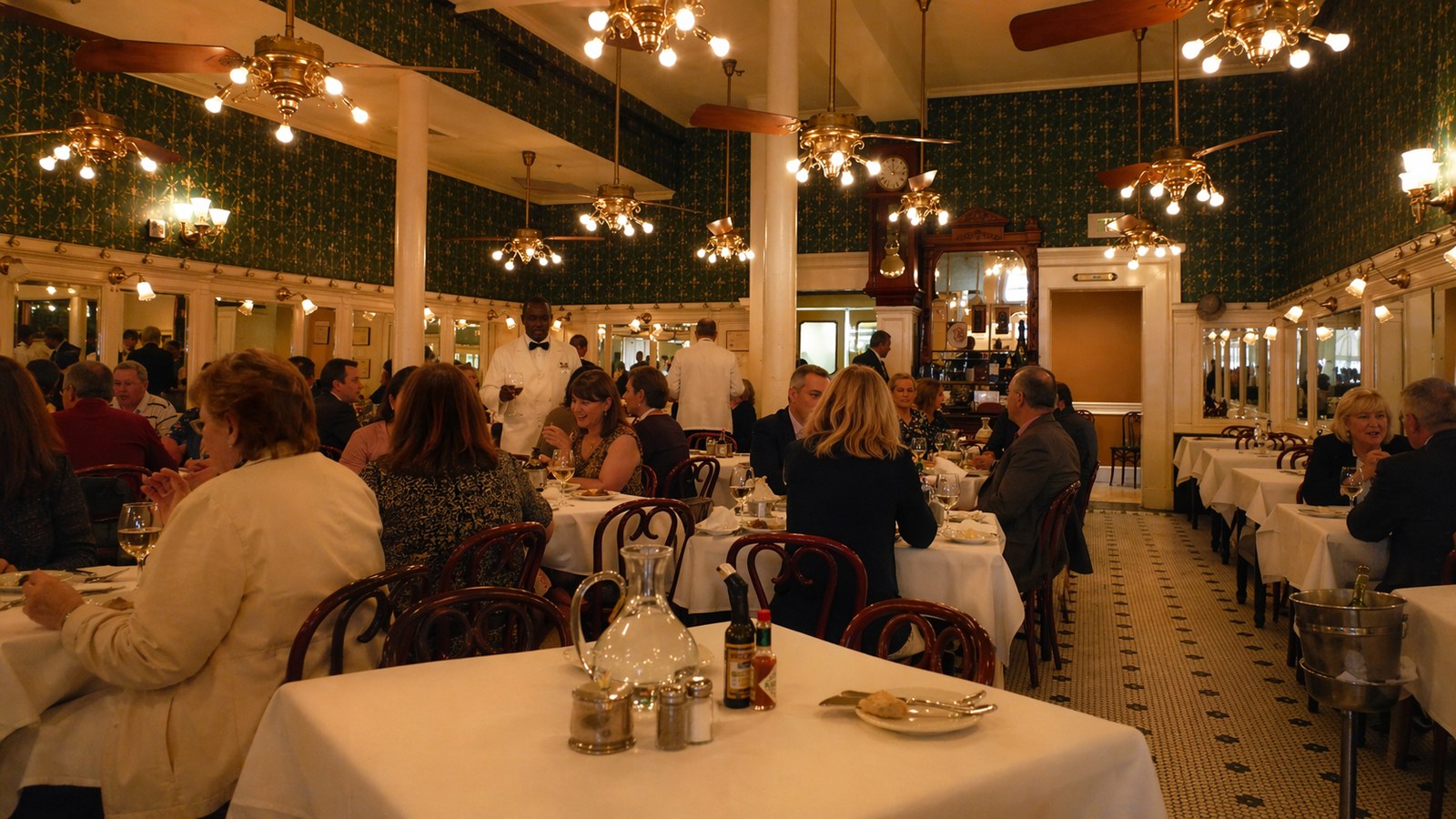Galatoire's — mirrored downstairs French Quarter dining room with white tile and ceiling fans